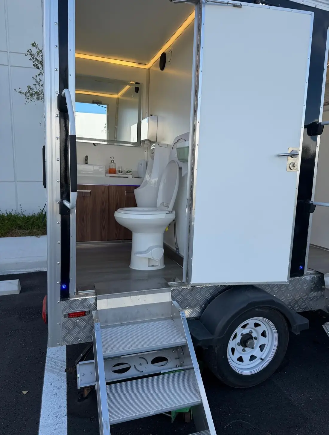 Restroom trailer interior with wood vanity, sink, mirror and toilet